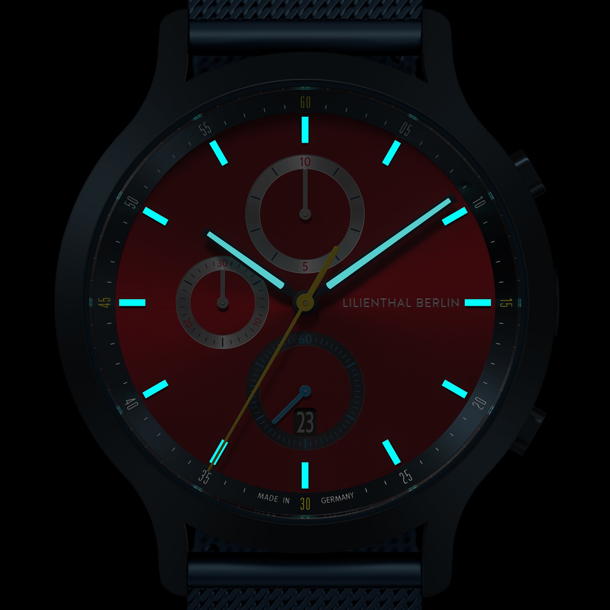 Red chronograph watch face with luminous blue hour markers and subdials in the dark