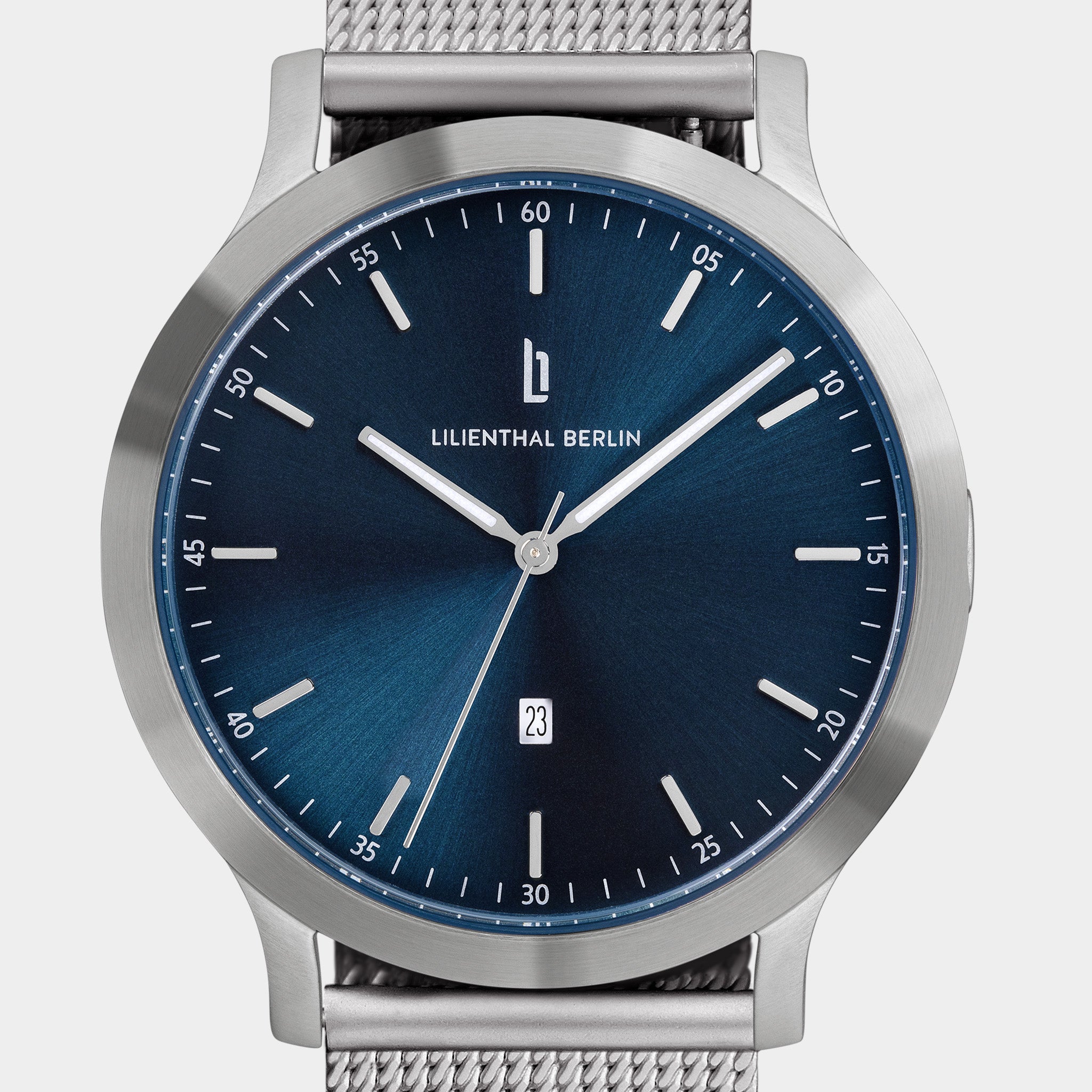 Minimalist steel watch with blue sunray dial, silver mesh strap, and date display