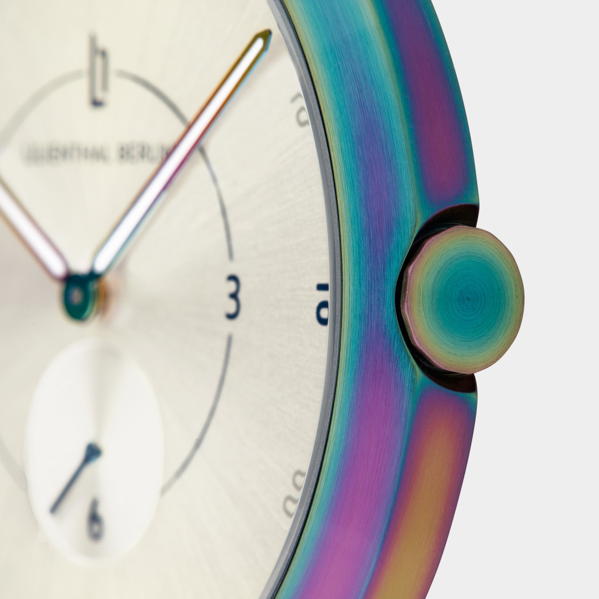 Close-up of a modern watch face with iridescent rainbow metal case and minimalist dial.