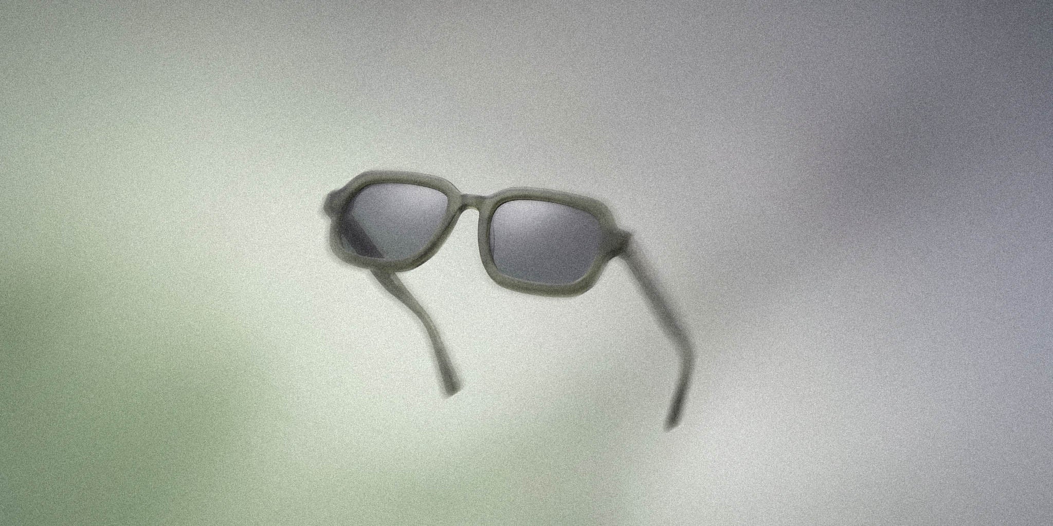 Stylish matte green sunglasses with dark lenses on a soft gradient background