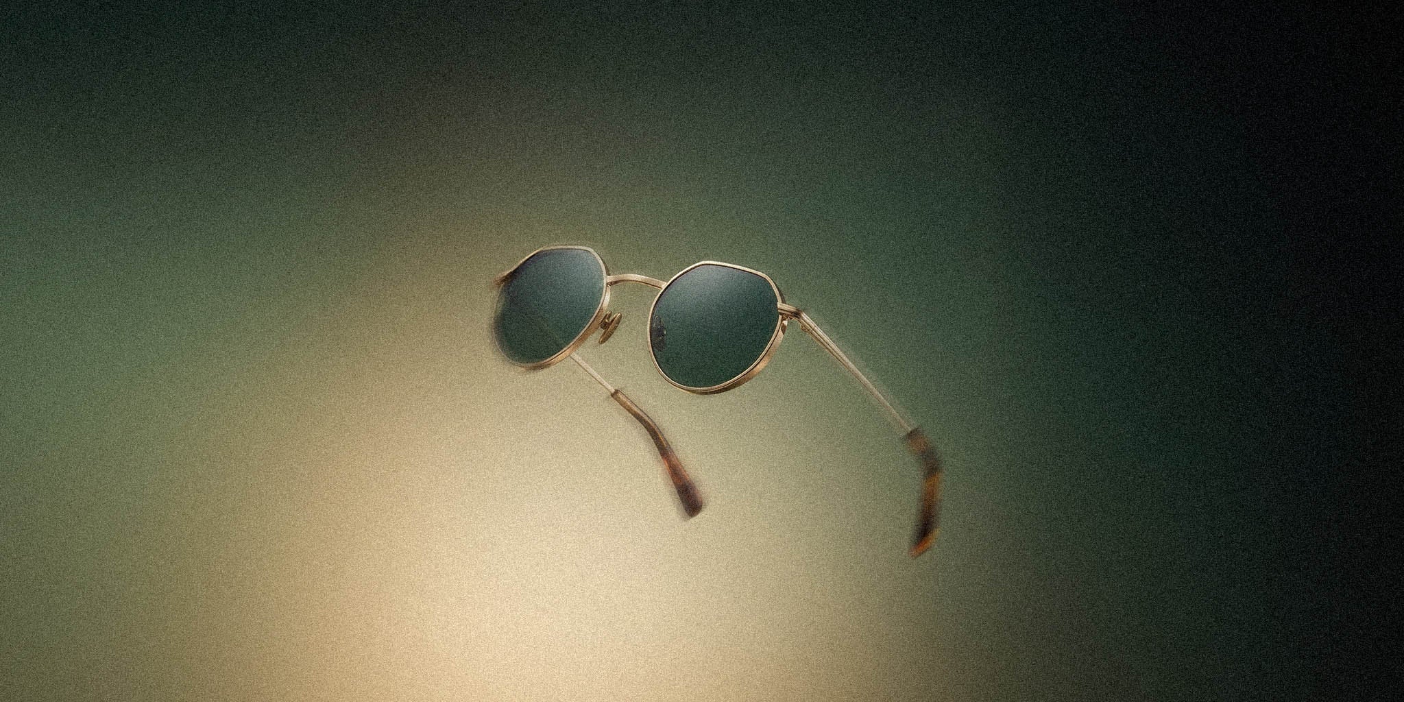 Round metal sunglasses with green tinted lenses floating on a gradient background