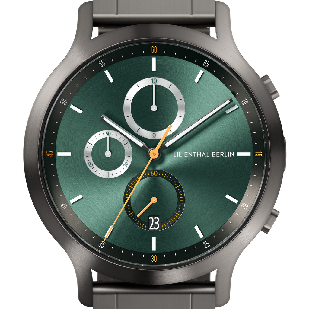 Green chronograph watch face with subdials, metal case, and date display