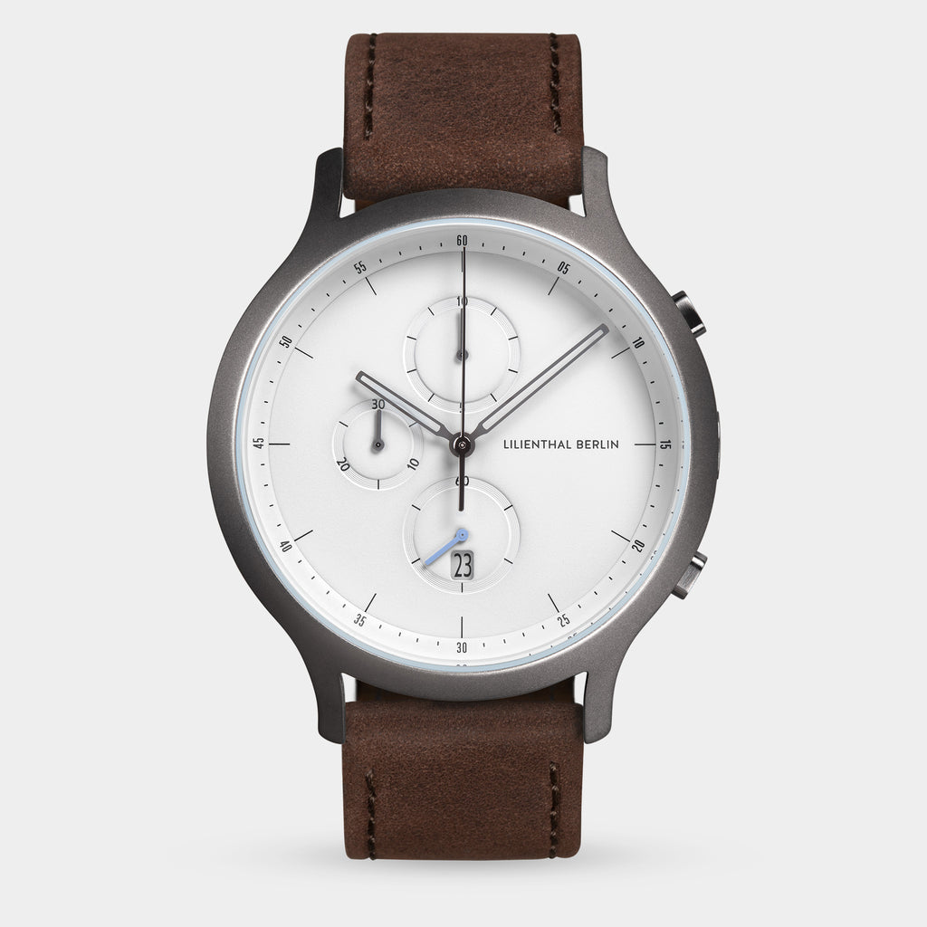 Minimalist men's wristwatch with brown leather strap, white dial, chronograph subdials, and date display