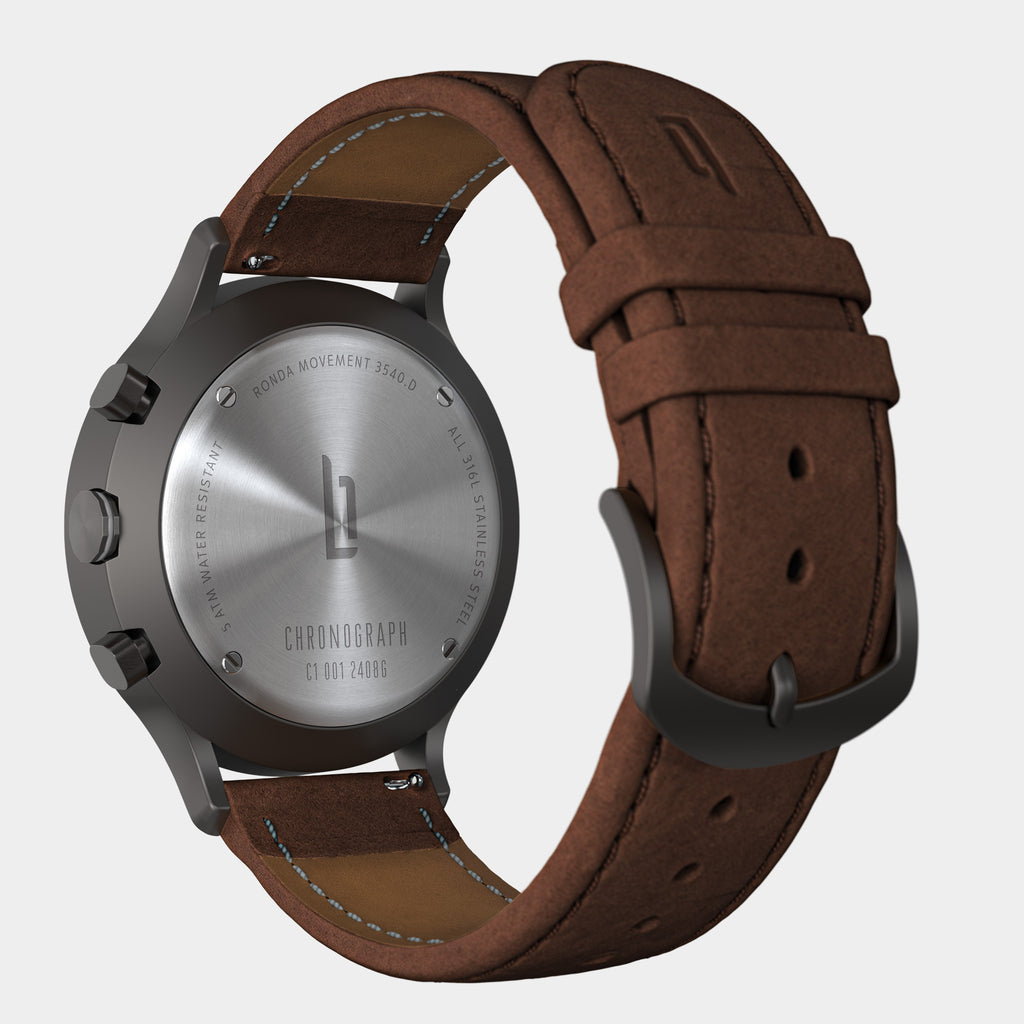 Close-up of chronograph watch case back with brown leather strap and stainless steel details