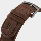 Close-up of brown leather watch strap with metal buckle and stitched detailing