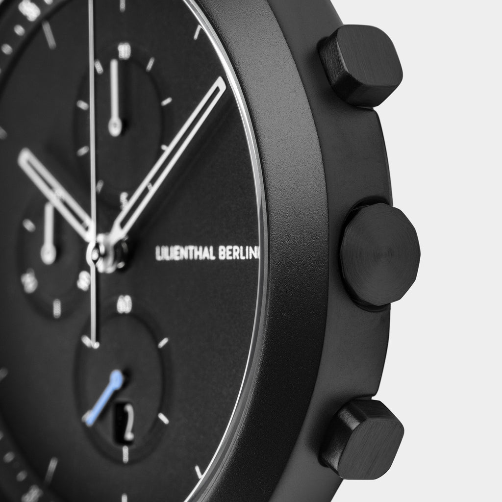 Close-up of a modern black chronograph watch face with pushers and subdials