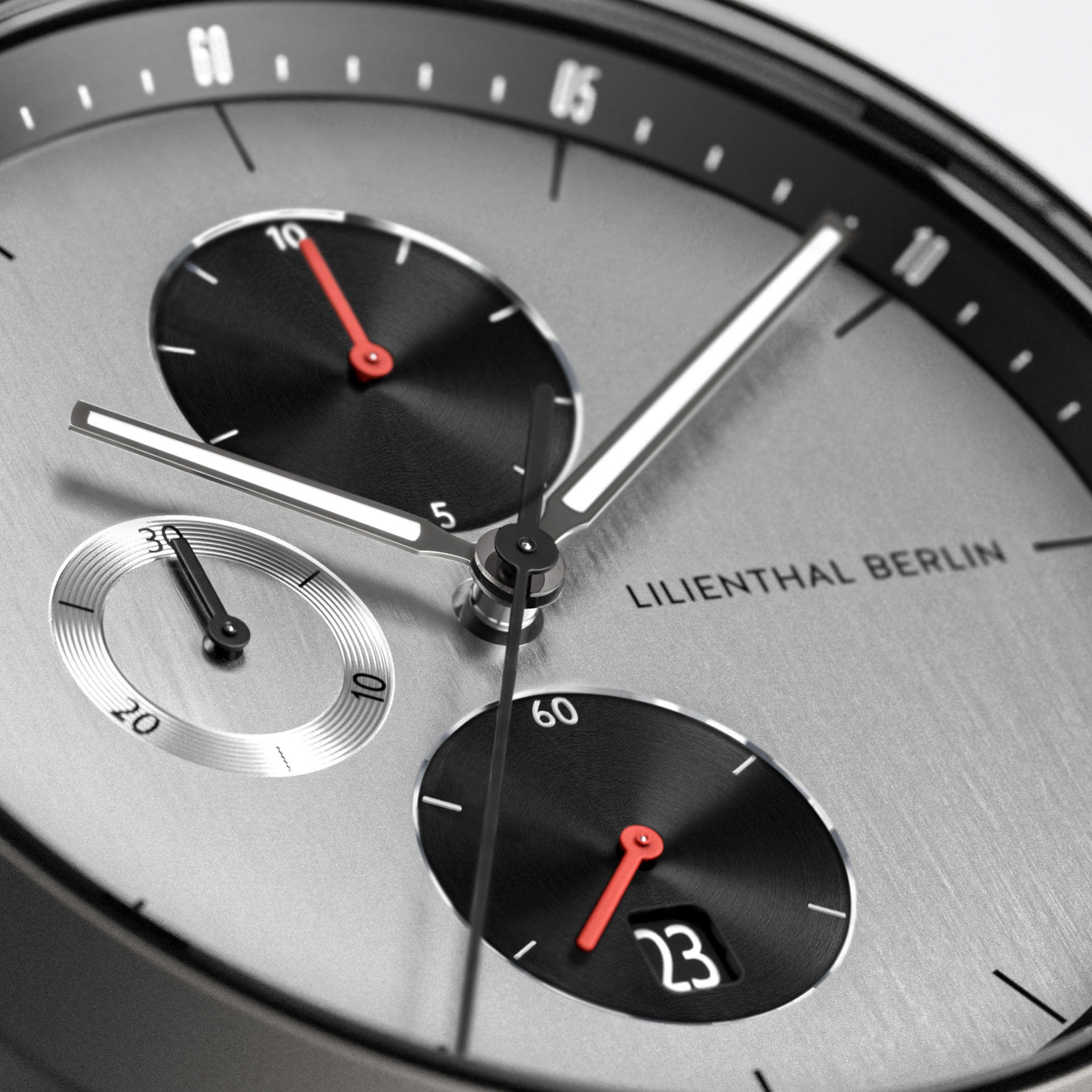 Close-up of a modern chronograph watch face with black subdials and red details.