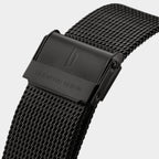 Close-up of black stainless steel mesh watch strap with embossed clasp and logo