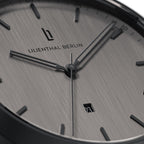 Close-up of a minimalist silver watch face with date display and black hour markers