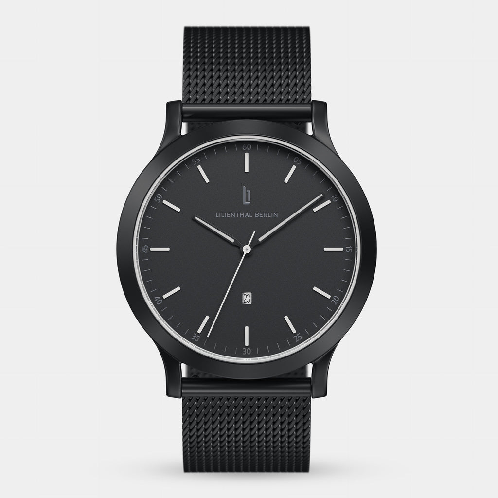 Minimalist black wristwatch with mesh strap and date display on white background