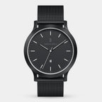 Minimalist black wristwatch with mesh strap and date display on white background