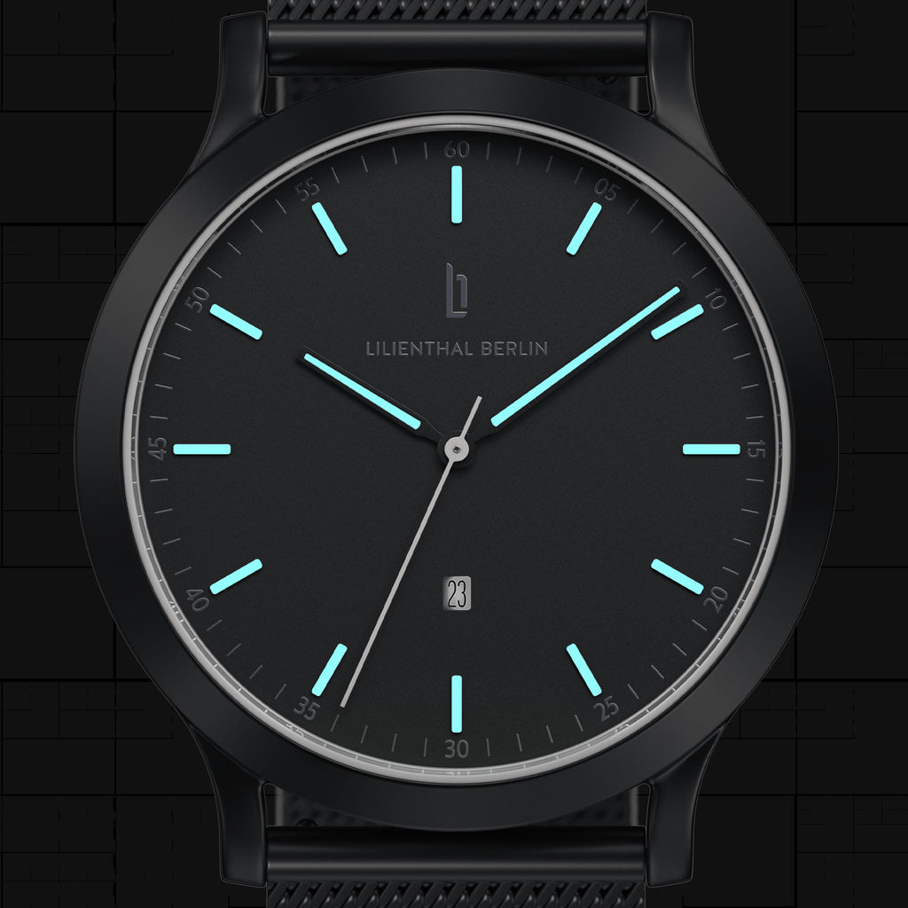 Minimalist black wristwatch with luminous blue hour markers and mesh strap