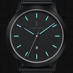 Minimalist black wristwatch with luminous blue hour markers and mesh strap