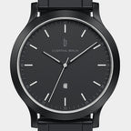 Minimalist black watch with black dial, silver hands, date display, and metal band