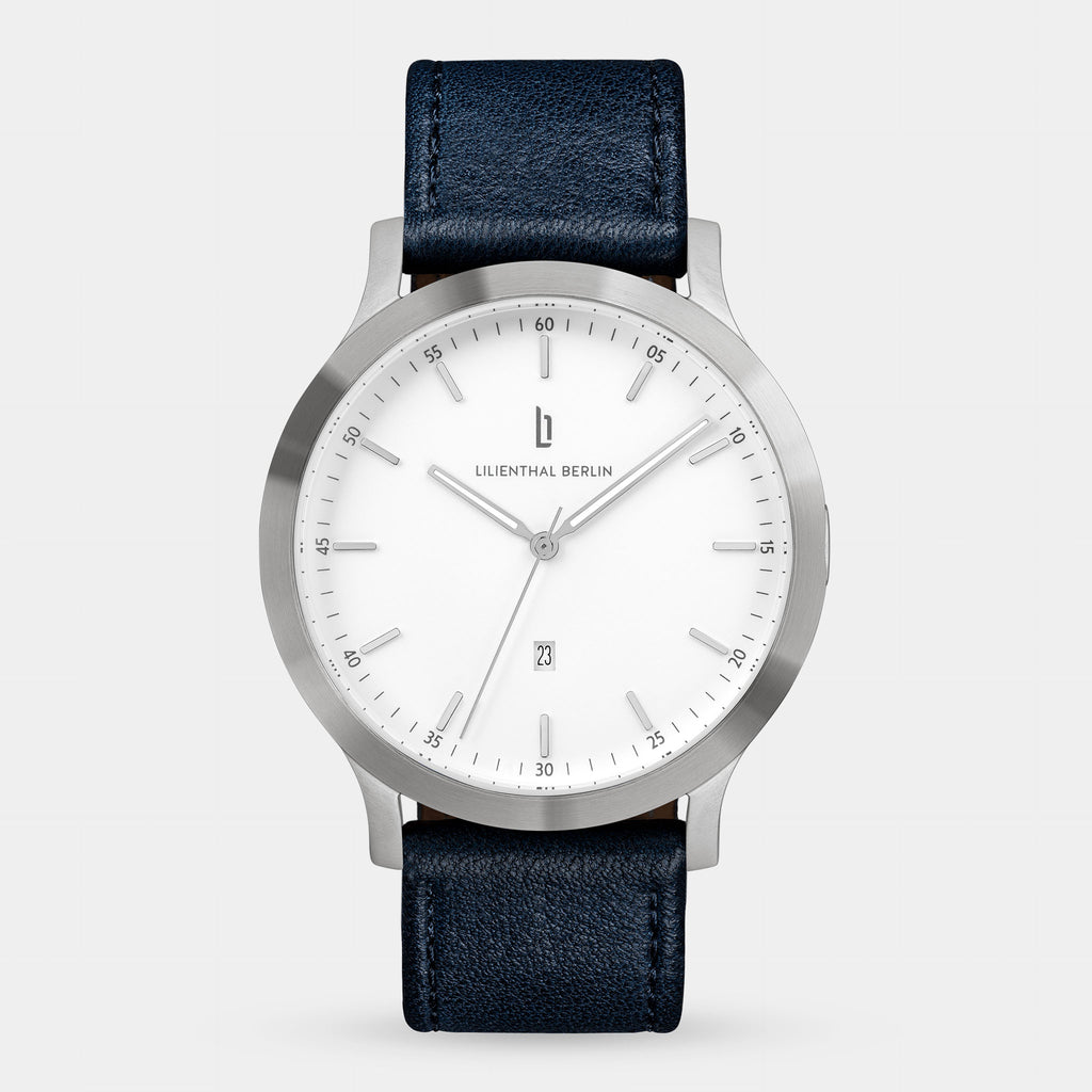 Minimalist silver wristwatch with white dial, date display, and black leather strap