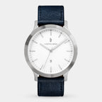 Minimalist silver wristwatch with white dial, date display, and black leather strap