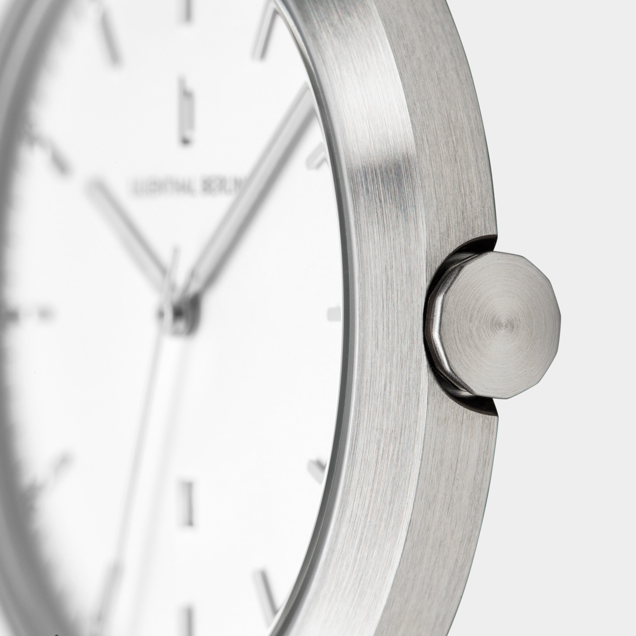 Minimalist silver watch close-up with brushed metal case and white dial