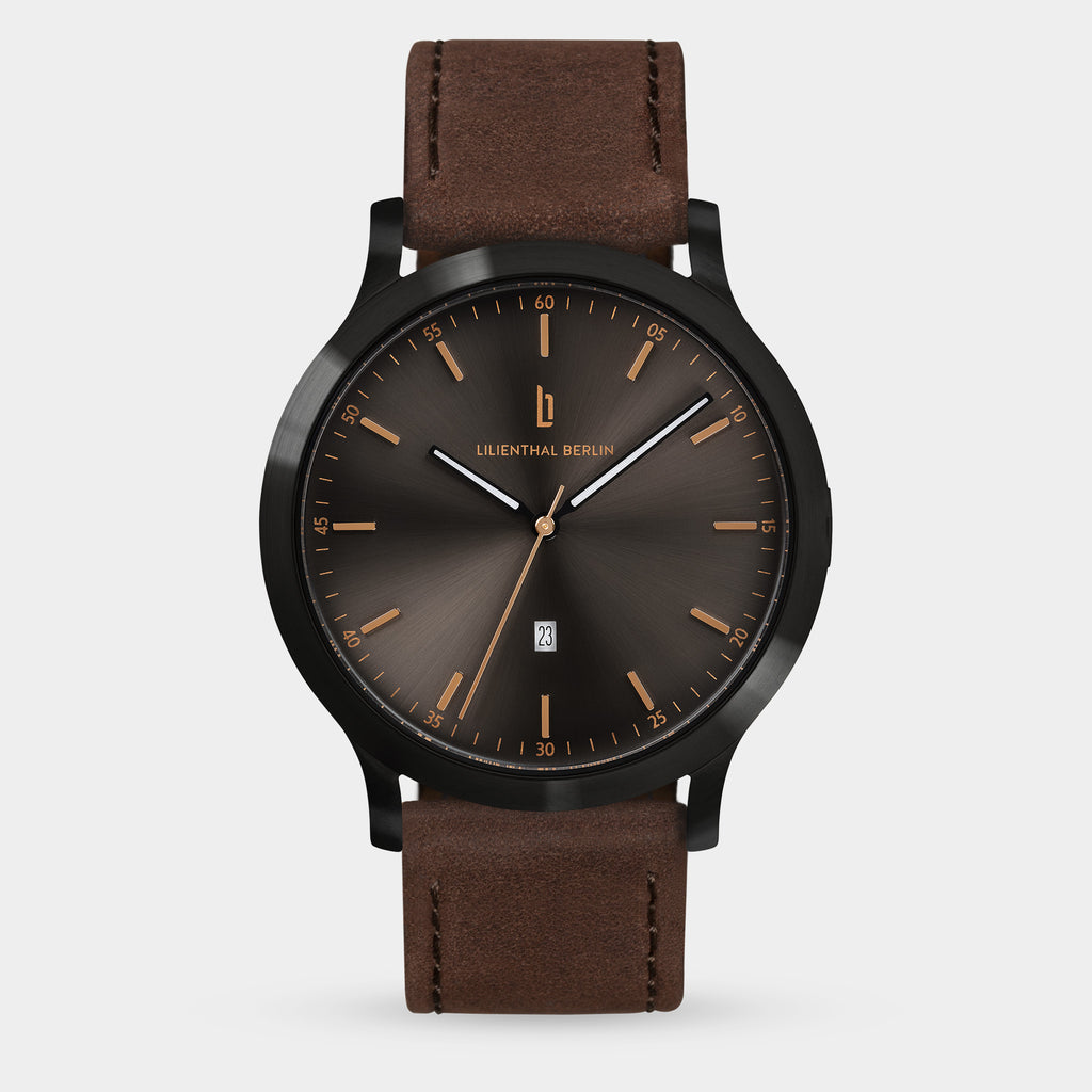 Minimalist men's watch with sunburst black dial, gold markers, and brown leather strap