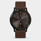 Minimalist men's watch with sunburst black dial, gold markers, and brown leather strap