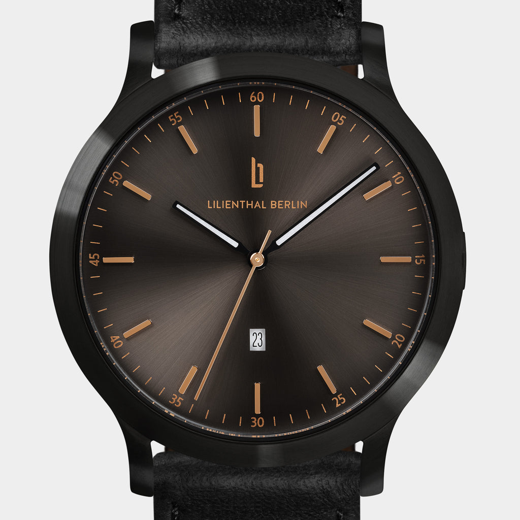 Elegant black watch with sunburst dial, gold hour markers, date display, and black leather strap