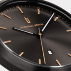Close-up of black minimalist watch face with gold hour markers, date display, and sleek hands