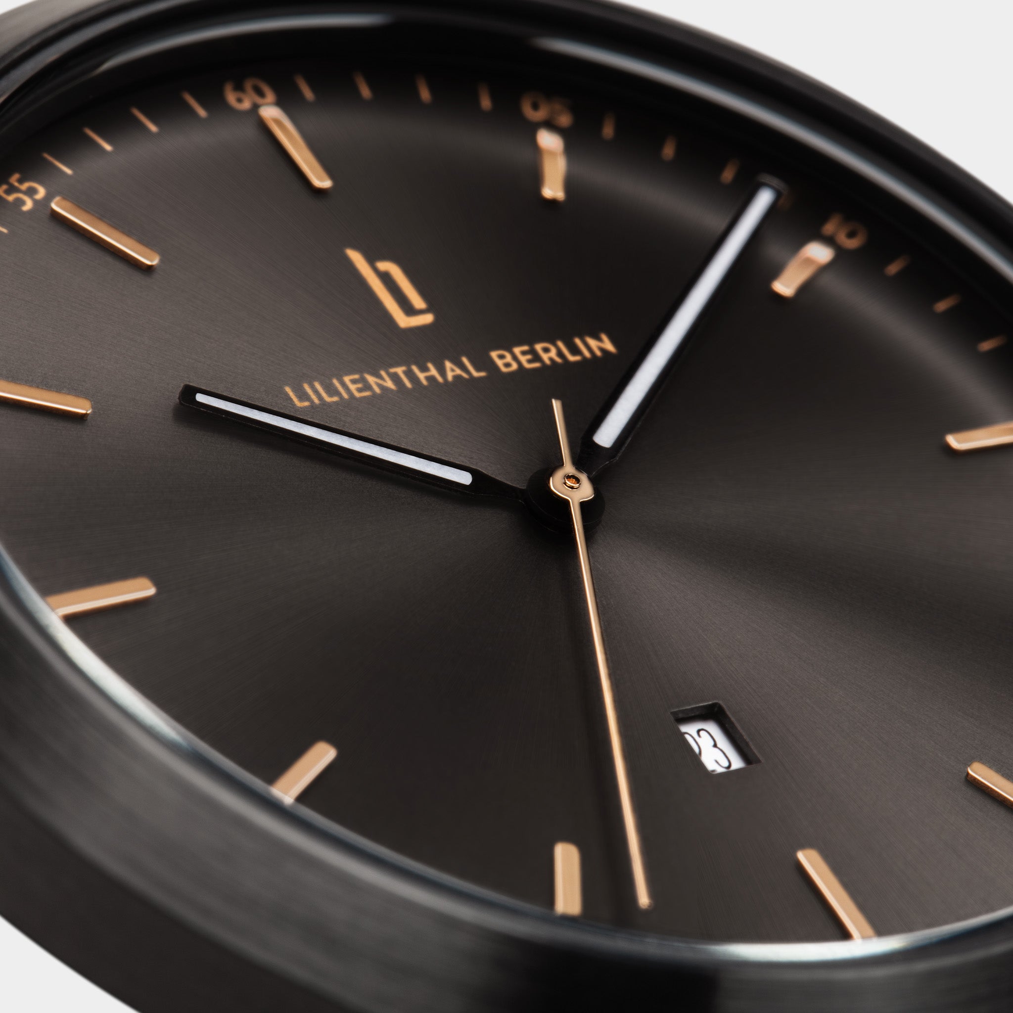 Close-up of black minimalist watch face with gold hour markers, date display, and sleek hands