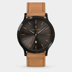 Men's analog wristwatch with black sunburst dial, gold markers, date display, and brown leather strap