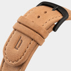 Close-up of a tan leather watch strap with black buckle and stitched edges
