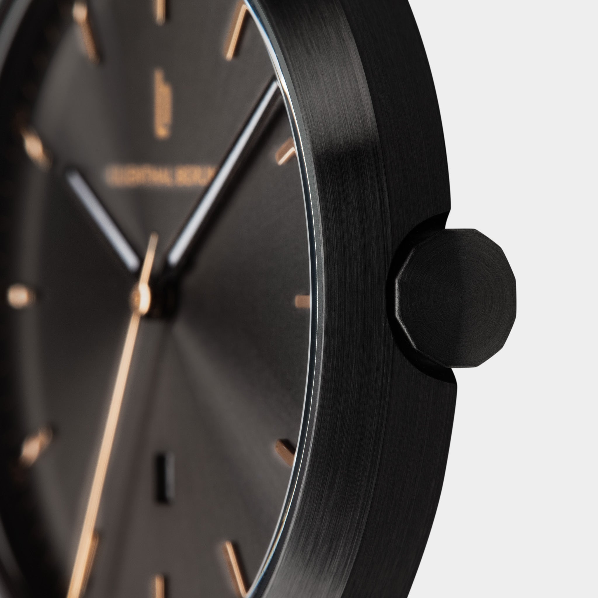 Close-up of a minimalist black wristwatch with gold hour markers and brushed metal case