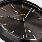 Close-up of a black minimalist watch with gold markers, date display, and sleek hands.