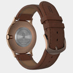 Back view of a rose gold case watch with brown leather strap and engraved stainless steel back