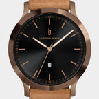 Elegant wristwatch with black dial, bronze case, gold hour markers, and tan leather strap