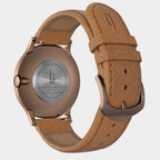 Close-up of a rose gold watch case with tan leather strap and engraved backplate