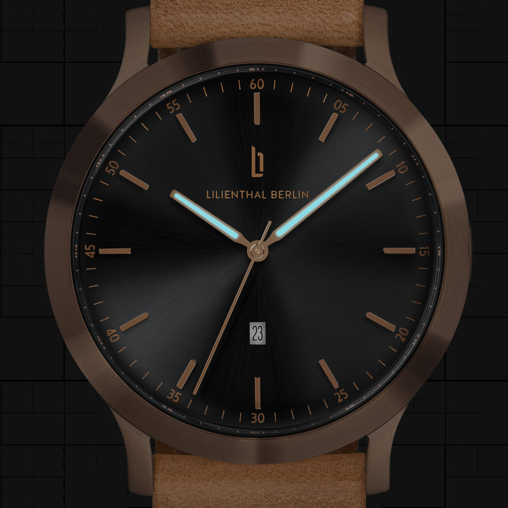 Elegant black dial wristwatch with gold case, date window, and light brown leather strap