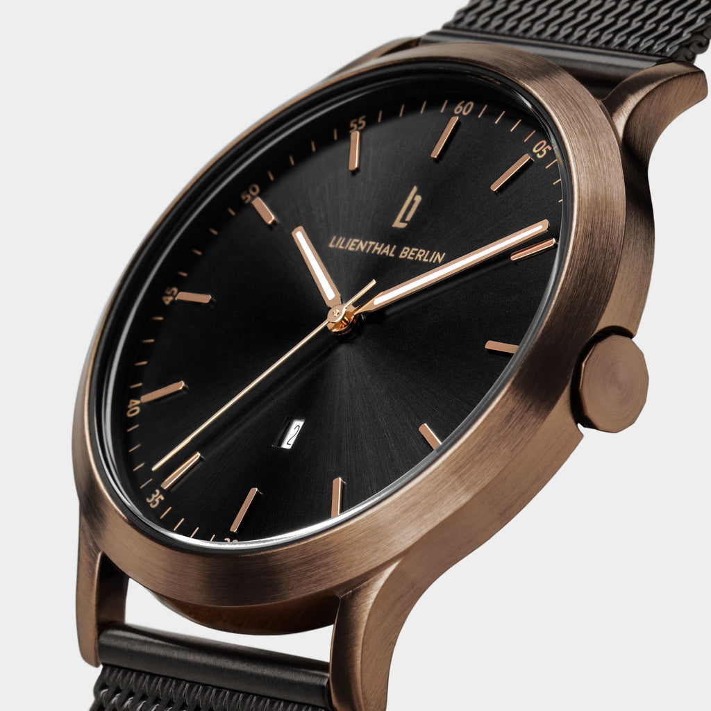 Elegant wristwatch with black dial, gold hour markers, mesh strap, and minimalist design
