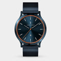 Blue mesh strap watch with black sunburst dial, orange accents, and minimalist design
