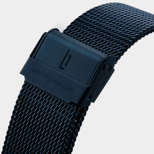 Black mesh metal watch strap with clasp and engraved logo, detail view