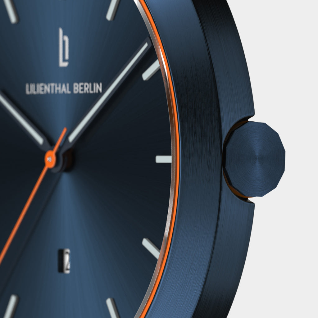 Close-up of a blue minimalist wristwatch with orange accents and a date display.