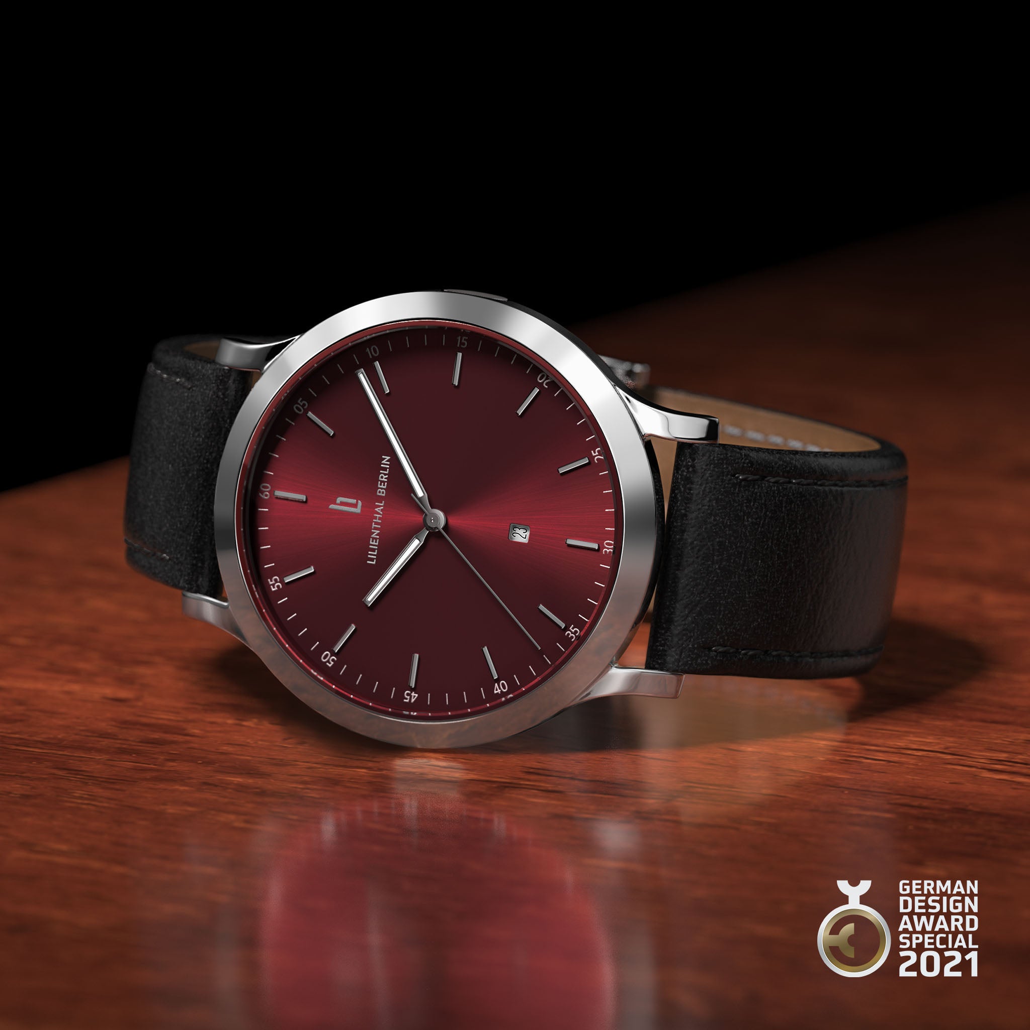 Minimalist wristwatch with deep red dial, silver case, black leather strap, German Design Award 2021 badge