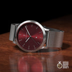 Minimalist silver mesh watch with burgundy dial on wood, German Design Award 2021 winner