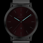 Minimalist wristwatch with black mesh strap, burgundy dial, luminous hands, and date display