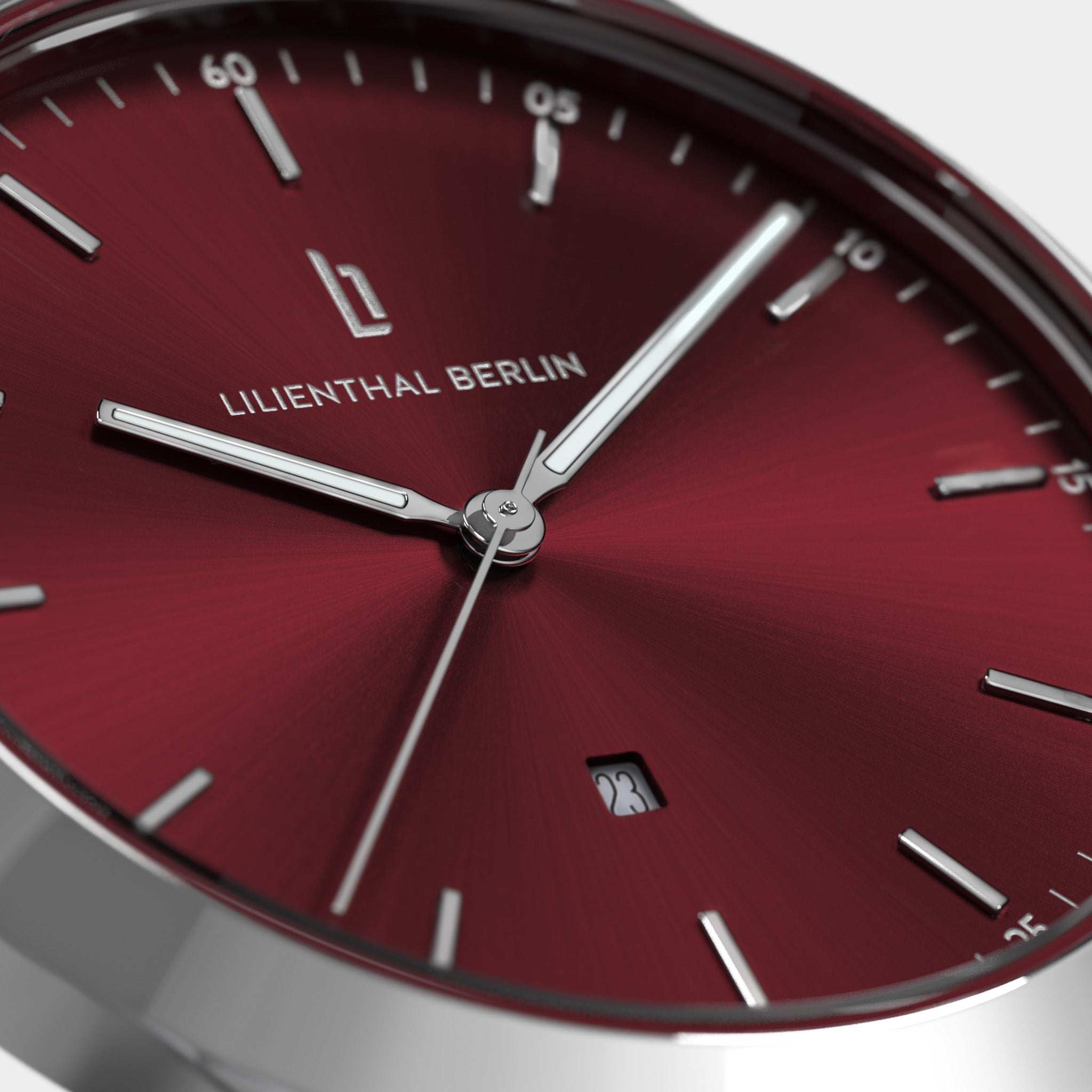 Close-up of a minimalist red watch face with silver hour markers and date display