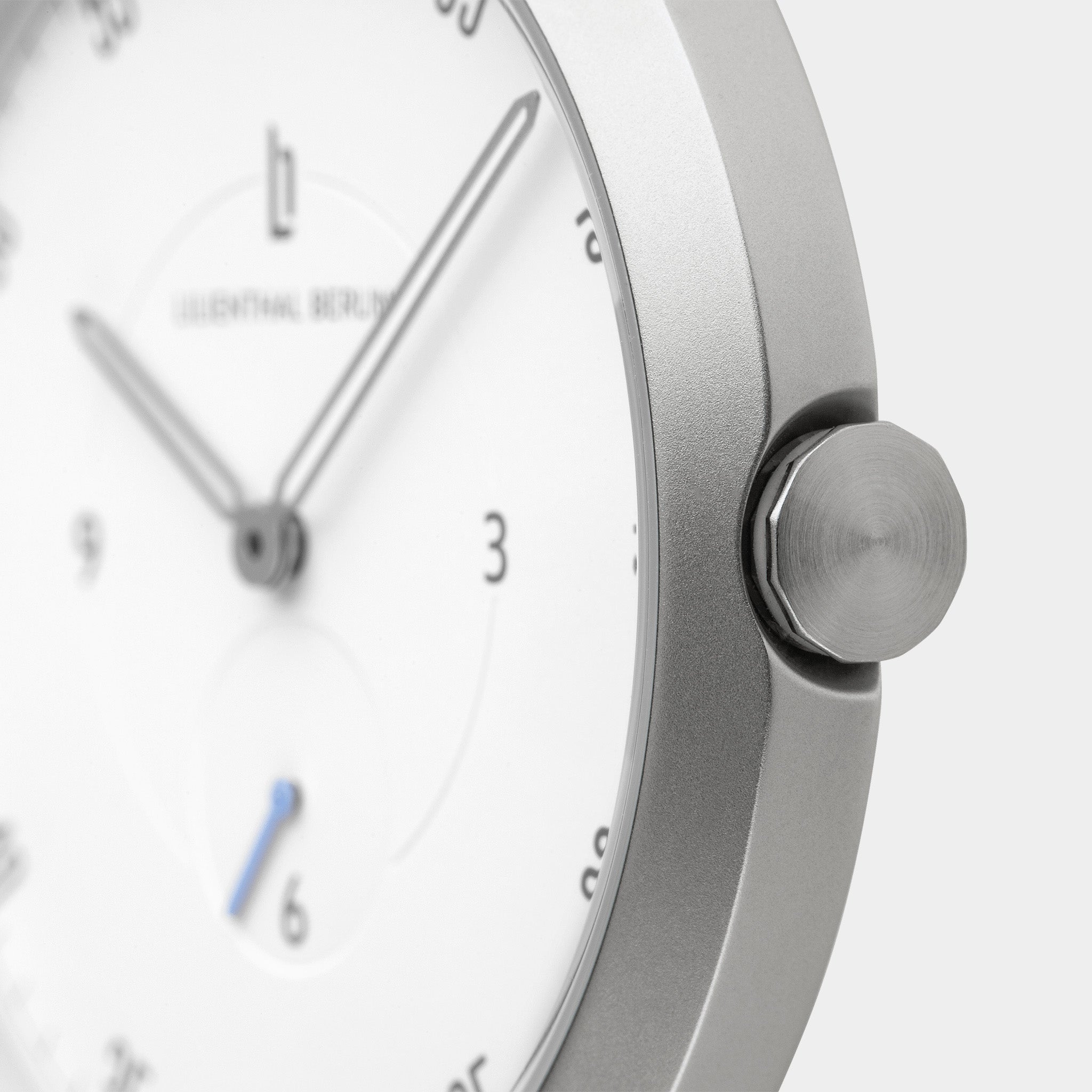 Minimalist silver wristwatch with white dial and sleek hands, close-up view