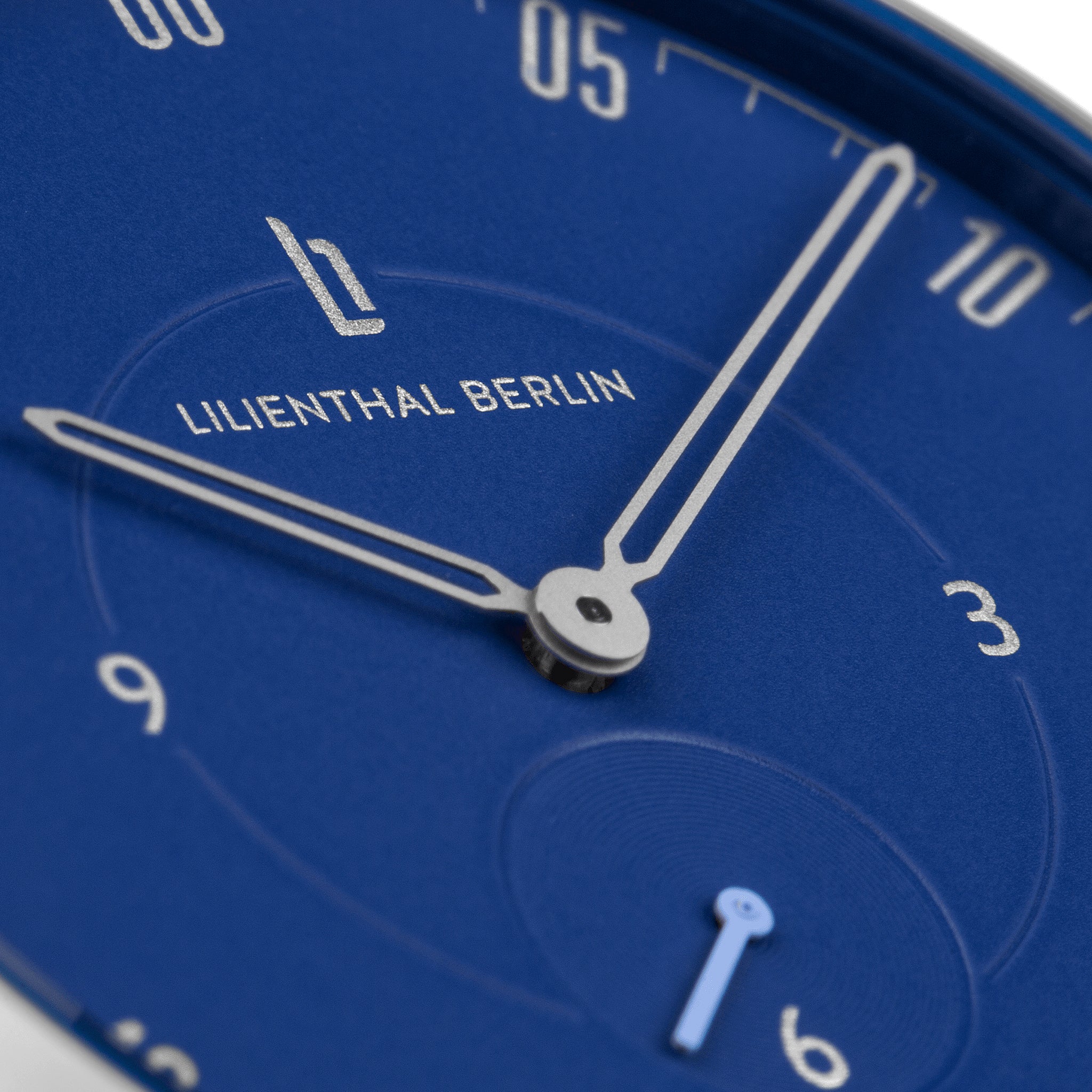 Close-up of blue minimalist watch face with silver hands and Lilienthal Berlin logo