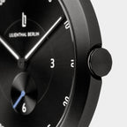 Close-up of minimalist black wristwatch with white markers and metallic crown
