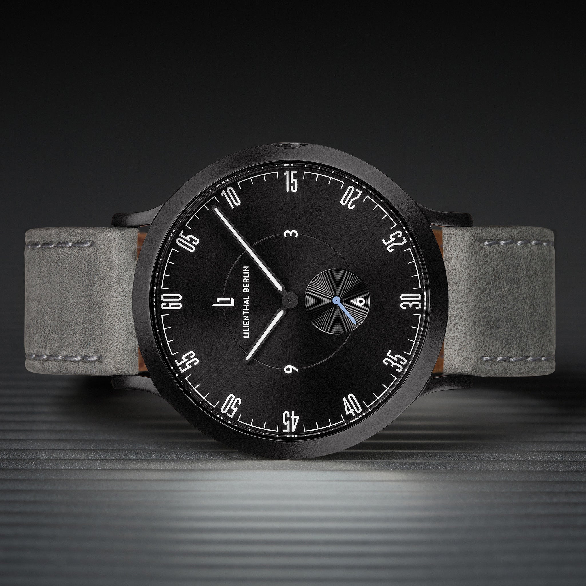 Minimalist black watch with grey leather strap, modern dial, and distinctive white markers