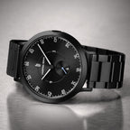Black minimalist wristwatch with black metal band on a metallic surface